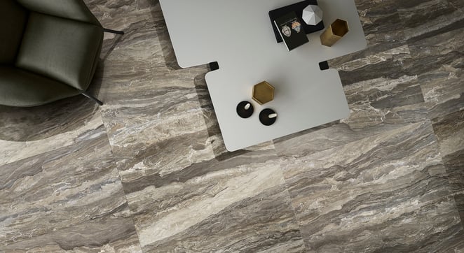 Taupe stone tiles with a natural, wavy pattern, a white table, and a green chair.